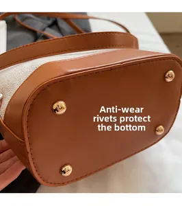 Detail of bag bottom with four gold protective studs on leather and canvas fabric