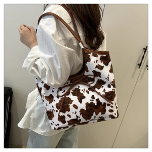 Detail of large tote bag featuring brown cow print pattern and side bow-knot ribbon tie