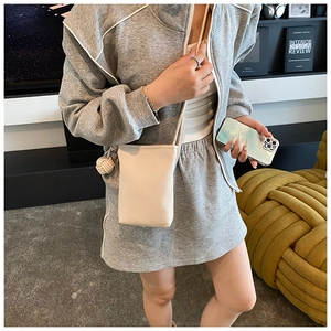 Close-up of cream white lychee texture crossbody phone bag with woven ball knot detail