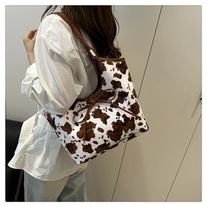 Detail of large tote bag featuring brown cow print pattern and delicate bow decoration