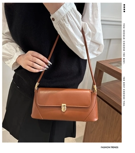 Detail of a brown leather shoulder bag with a stylish gold square clasp and thin strap