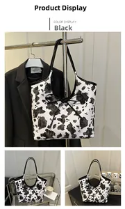 Detail view of large tote bag featuring a cow print pattern and black drawstring bow detail