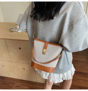 Detail of vintage canvas bucket bag with brown leather trim and gold metallic buckle