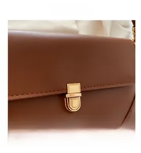Macro detail of brown leather shoulder bag with gold metal clasp and stitching