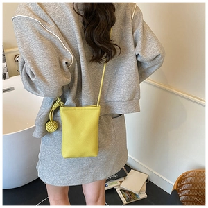 Detail of yellow pebbled leather mini crossbody bag with decorative side knot accents