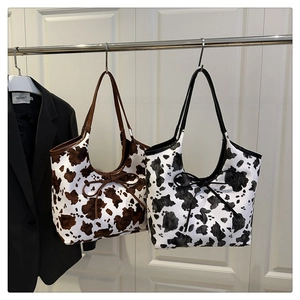 Detail of cow print tote bags with bow drawstrings in brown and black leather finishes