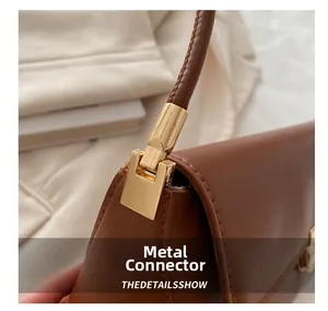 Close-up of golden metal connector on a brown leather handbag with strap detail