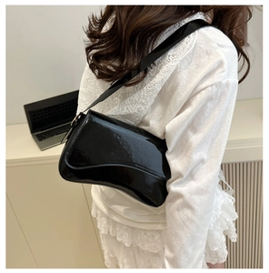 Chic black patent leather shoulder bag styled on model with a glossy minimalist finish