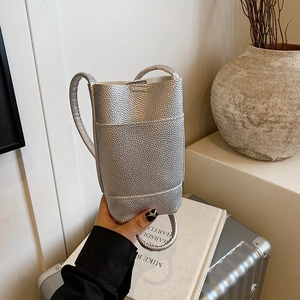 Silver lychee pattern mini crossbody bag held against a minimalist aesthetic backdrop