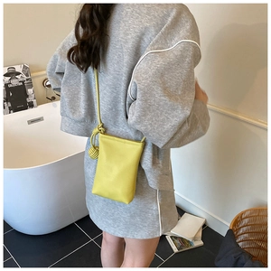 Detail of a bright yellow mini crossbody bag with knot shoulder strap on a model