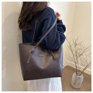 Detail of vintage brown leather tote bag showing fashion brand plaque and texture