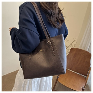 Dettaglio della borsa tote marrone scuro con texture vintage e dettagli metallici oro