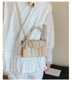 Detailed view of beige woven crossbody bag with decorative knot handle on a model