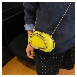 Detail of yellow oval crossbody bag featuring a gold U-shaped handle and metal chain strap