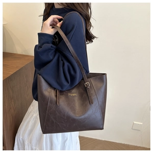 Dettaglio della borsa tote marrone scuro con trama vintage e scritte dorate sulla pelle