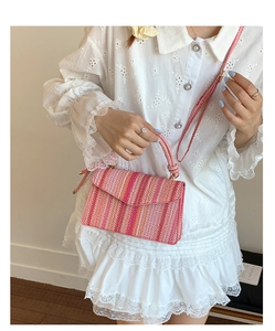 Detailed shot of a striped straw crossbody bag in pink and orange tones with woven handle