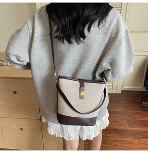 Model view of canvas bucket bag with brown leather trim and golden metal turn-lock