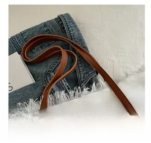 Detail of comfortable brown leather handles on a white canvas tote bag with fringe