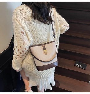 Detail of vintage canvas bucket bag with brown leather trim and golden metal clasp