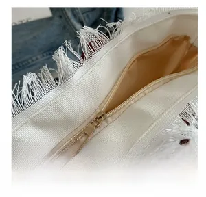 Close-up of a high-quality smooth metal zipper and fringe edge on a white canvas tote bag