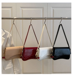 Detail of four glossy patent leather shoulder bags in beige, burgundy, white and black colors