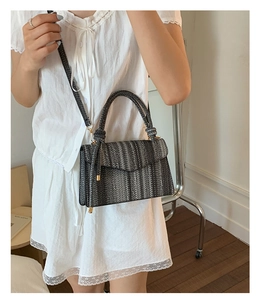 Detail of grey woven crossbody bag with striped texture worn on white lace dress