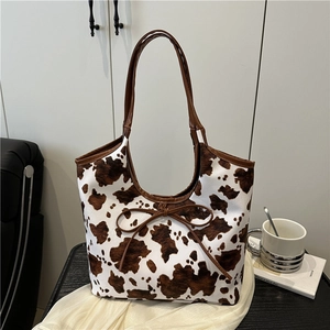 Large cow print tote bag with brown handles and bow detail for summer commuting