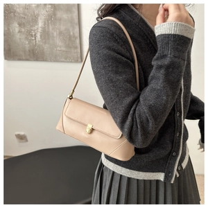 Detailed view of beige baguette shoulder bag with elegant golden metallic buckle closure
