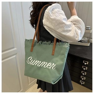 Detail of green canvas tote with Summer embroidery and stylish fringe trim detail