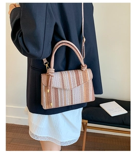 Detail of woven crossbody bag showing earth-tone stripes and gold-tone hardware