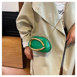Detail of a bright green mini crossbody bag featuring a unique gold streamline handle