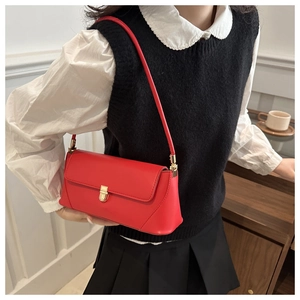 Detailed view of red rectangular underarm bag with gold lock and adjustable strap
