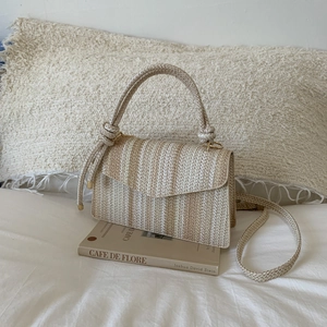 Detail view of woven striped texture and braided handle of the beige crossbody bag