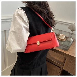 Close-up of stylish red baguette shoulder bag with gold metal buckle and sleek strap