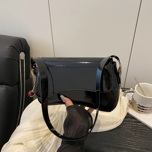 Minimalist black patent leather crossbody bag for women with a red cherry charm