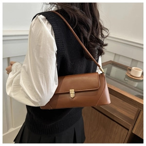 Detailed side view of vintage brown leather underarm bag with gold metal buckle