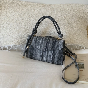 Detail of multi-color woven straw crossbody bag with gold metal buckle on a cozy background