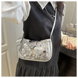 Macro shot of silver sequin shoulder bag with round metallic texture and golden buckle