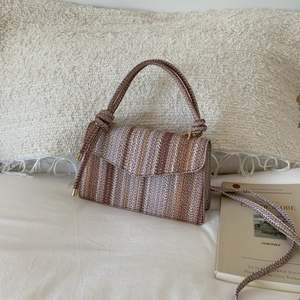 Close-up of woven crossbody bag with vertical brown stripes and golden hardware