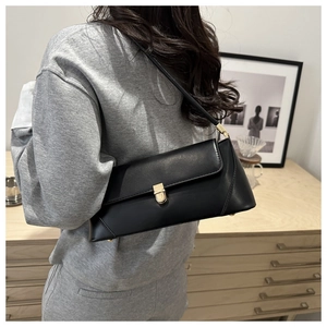 Minimalist black baguette shoulder bag with gold square buckle shown on a model