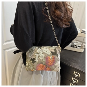 Detail shot of green and orange sequin leaf patterns on a luxury chain shoulder bag