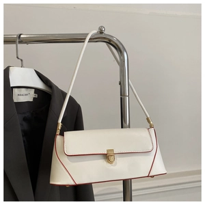 Detail of white leather baguette bag with red trim and golden twist-lock closure