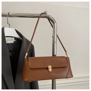 Close-up of brown faux leather baguette bag with golden metal buckle on a hanger