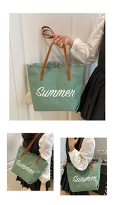 Detail of green canvas tote with Summer embroidery and fringe edges on a leather handle