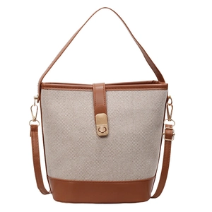 Minimalist canvas bucket bag with brown leather trim and metal swivel lock on white background