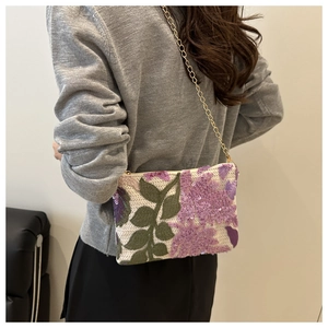 Detail of floral sequin embroidery and slim gold chain on the stylish evening bag