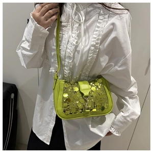Detail of neon green sequin shoulder bag with silver buckle worn on a white blouse
