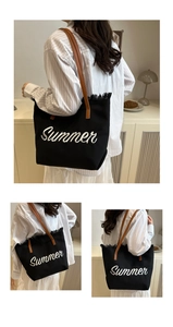 Close-up of black canvas tote bag with Summer embroidery and brown leather straps