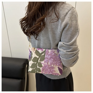 Detail of purple floral sequin embroidery on small square bag with gold chain strap