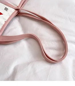 Detail of pink leather handles and neat stitching on a clover pattern tote bag